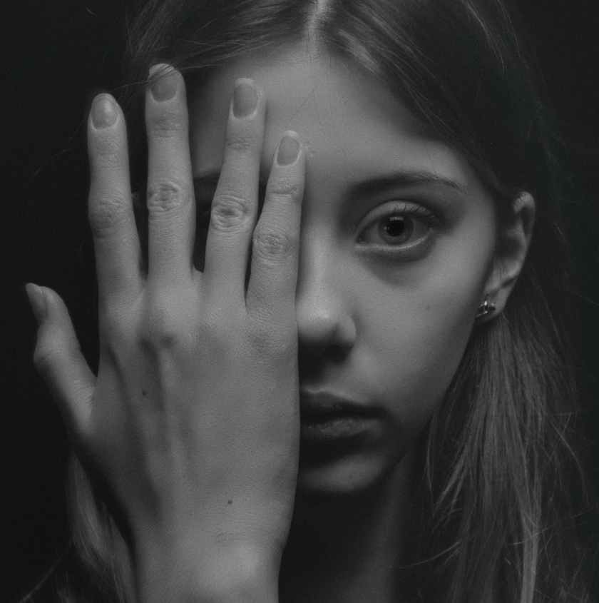 grayscale photo of woman covering her face by her hand